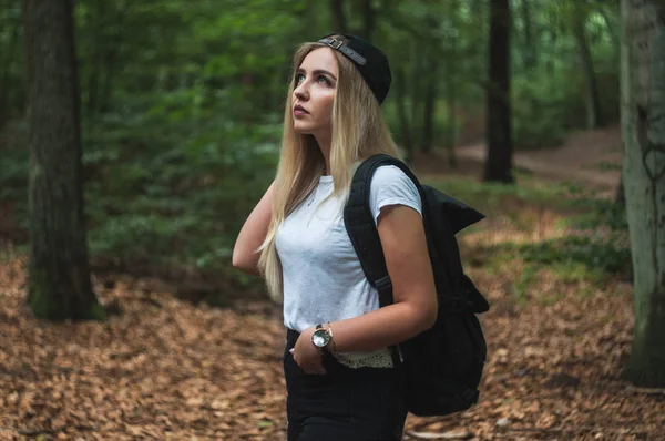 Traveling woman with backpack and peaked cap. Forest Gdansk.