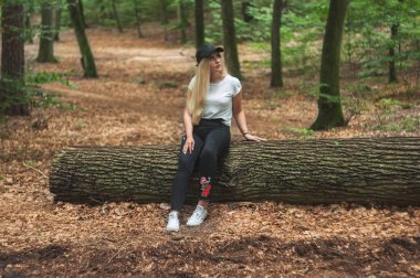 Genç kadın oturup orman içinde ağaç