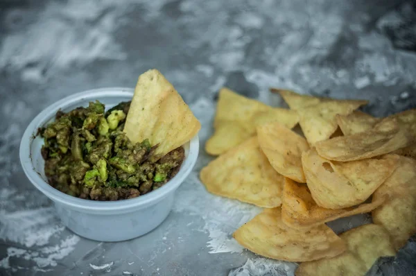 Geleneksel Latin Amerika Meksika soslu guacamole killi kasede ve koyu arka planda yarım avokado.