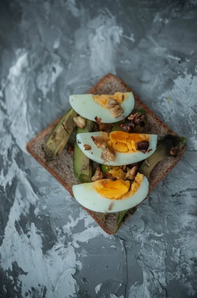 Çavdar ekmeği, dilimlenmiş avokado, fındık ve yumurta ile kahvaltı veya öğle yemeği için sağlıklı avokado tost. Vejetaryen sandviçler. Bitki bazlı diyet. Tüm gıda konsepti.