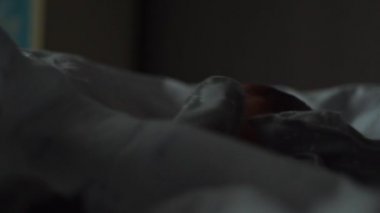 Yeni doğan akşam beşikte sakince yatar. Bebek bir battaniyeyle örtüldü. Yumuşak loş ışık.