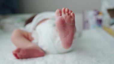 Yeni doğmuş bir bebeğin küçük bacakları. Bebek bacağını oynatıyor. Defoktus. Yeni bir hayat. Bezli bebek kundaklama masasında.