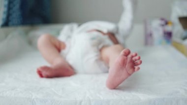 Yeni doğmuş bir bebeğin küçük bacakları. Bebek bacağını oynatıyor. Defoktus. Yeni bir hayat. Bezli bebek kundaklama masasında.