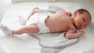 Bezli ve çoraplı yeni doğmuş bir bebek soyunma masasında yatıyor. Sargılı göbek bağı. Bebek doğduğunda hayatın ilk anları.