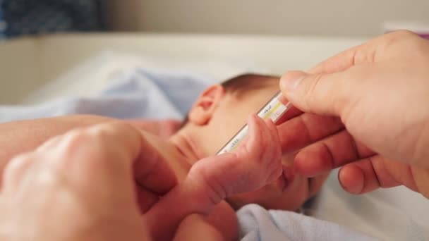 Madre o padre midiendo la temperatura del bebé con termómetro de mercurio. El niño tiene varios meses de edad. Temperatura normal del bebé. La piel seca del niño . — Vídeos de Stock