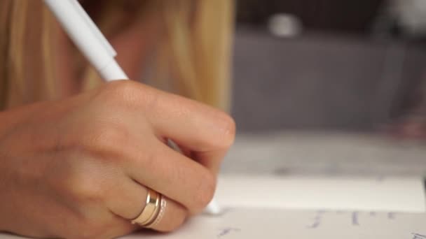 La chica toma notas en un cuaderno. La mano escribe. Chica haciendo su tarea. Estudio remoto. Mujer hace planes para el futuro, haciendo la investigación académica preparándose para el examen de los cursos de estudio en casa en una cama — Vídeos de Stock