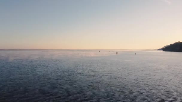 Vista aérea do rio ou do mar no início da manhã. Superfície de água com ondas e nevoeiro. Bóias num lago. Pescadores a pescar. Gradiente no céu — Vídeo de Stock