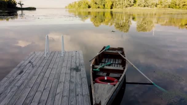 Oldtimer-Holzboot mit rotem Rettungsring, das am Ufer eines Sees festgemacht hat. Kamera fliegt über ein Boot — Stockvideo