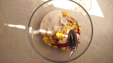 Taze kırmızı biberli tavuk salatası ve bir kasede mısır, sağlıklı, enerjik, besleyici. Sağlıklı kahvaltı, sağlıklı beslenme. Erkek eli salataya sos döker.