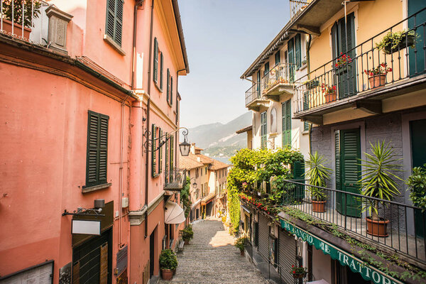 Bellagio. Lake Como. Italy - July 21, 2019: Amazing Old Narrow Street in Bellagio with Shops. Italy. Europe. Famous Picturesque Cobblestone Street with Souvenir Shops, Restaurants and Cafes.