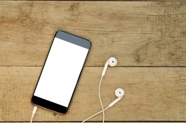 Ahşap masa üzerinde kulaklık ile akıllı telefon. Beyaz ekran.