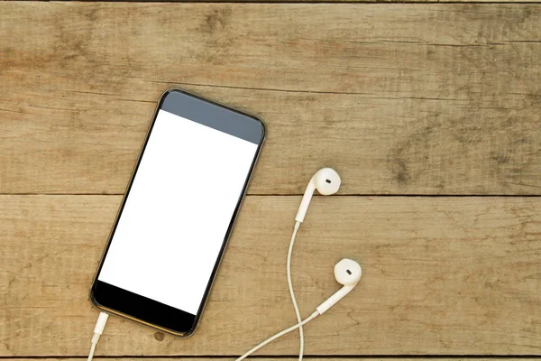 Ahşap masa üzerinde kulaklık ile akıllı telefon. Beyaz ekran.