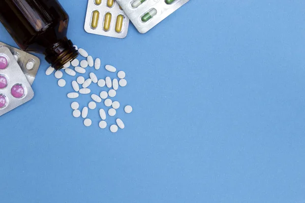 Hap hap şişe mavi arka plan üzerinde tıbbi tablet ile dışarı dökülen.