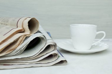 Gazeteler ile kahve fincanı beyaz zemin üzerine yığını.