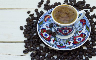 Türk kahve fincanı ve ahşap beyaz zemin üzerine kahve çekirdekleri.