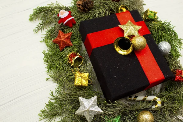 Beyaz arka planda siyah hediye kutusu ve Noel süslemeleri.