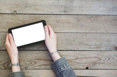 Dijital tablet ile boş perde ahşap bir masa üzerinde tutan eller kadın.