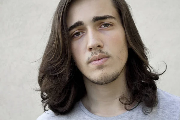 Long haired young handsome male looking at camera.