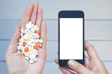 Renkli hapları ve ilaçlar ile smartphone kadın elinde.