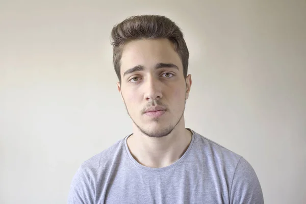 Yakışıklı delikanlı gri arka plan üzerinde izole kamera bakarak portresi.