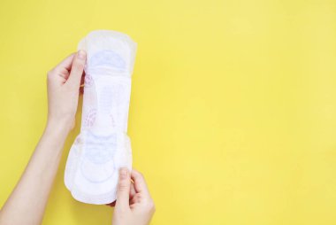 Sarı izole arka planda kadın elleri pedi tutuyor.