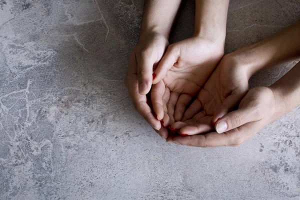 Open hands of man and woman with palm up grey background.