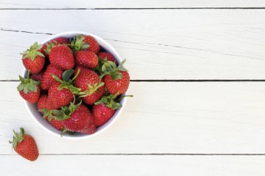 Beyaz ahşap arka plan üzerinde seramik kase taze çilek.
