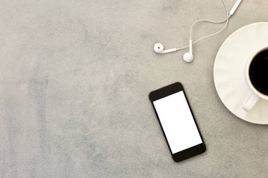 Gri arka planda cep telefonu, kahve fincanı ve kulaklık.