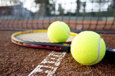 Kil tenis kortundaki tenis raketleri ve topları. Yakın çekim.