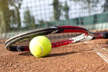 Kil tenis kortundaki tenis raketleri ve topları. Yakın çekim.