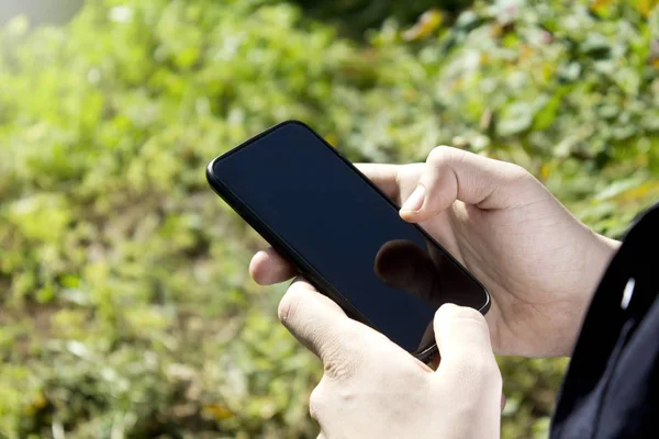 Bahçe arka planda cep telefonu tutan erkek eller.