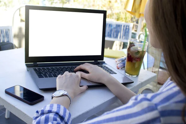 Bir kafede dizüstü bilgisayar üzerinde çalışan genç kadın.