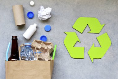 Geri dönüşüm sembolü ve gri arka plan üzerinde farklı çöp. Üstte görüntü.