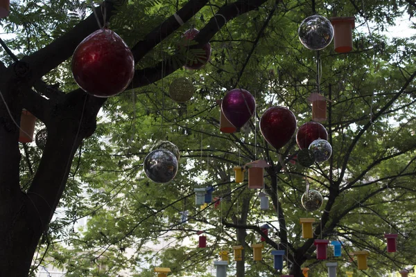 Adorned street trees. There are decorative balls, balloons, lamps and oil lamp