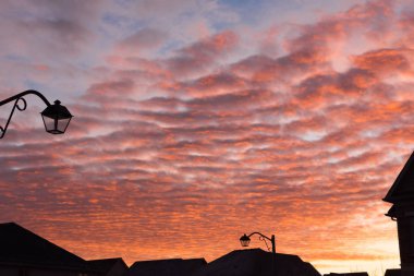 Red yellow clouds lit by the rays of the morning sun covered the sky over the city