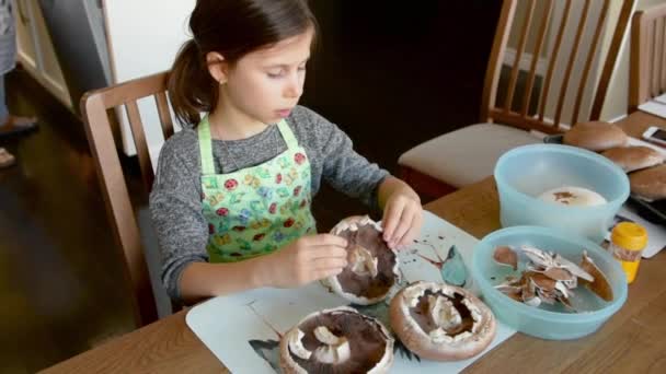 소녀는 버섯을 튀기기 준비하고 껍질을 그릇에 담는다 — 비디오