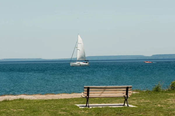 Ensam bänk på stranden och en Yacht vid horisonten — Stockfoto