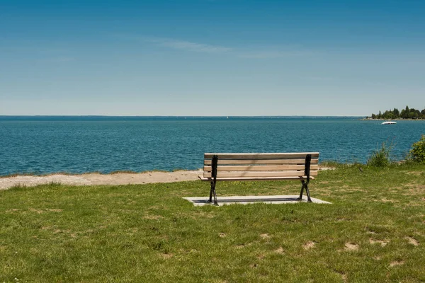 Büyük bir gölün kıyısında yalnız bank — Stok fotoğraf
