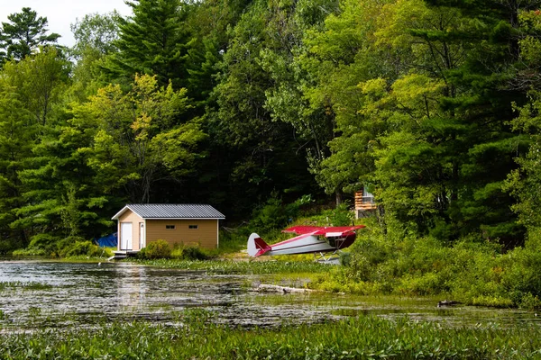 Un pequeño hidroavión se encuentra en el borde del lago cerca de la casa — Foto de Stock