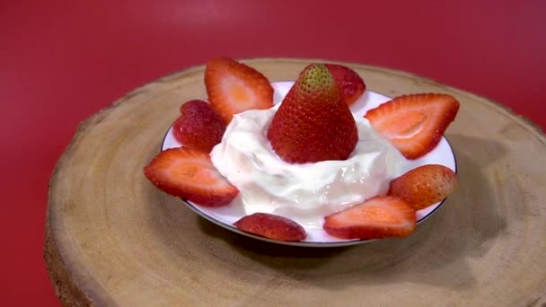 접시와 나무판 신크림을 딸기는 배경에서 회전한다 — 비디오