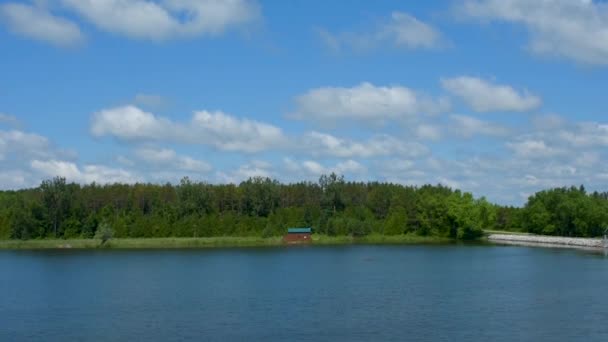 Beau panorama sur un lac et une forêt verte en arrière-plan sous un ciel bleu avec des nuages blancs