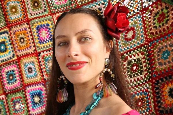 Beautiful gypsy woman in red with a red rose in her head on a bright background