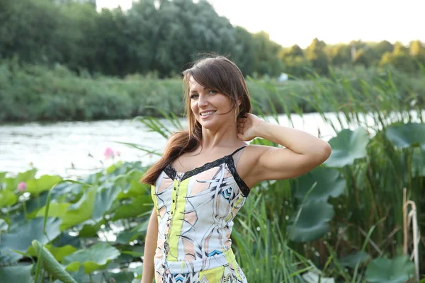 young brunette girl on a lake with reeds and lilies on vacation