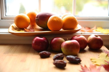 taze meyve mango, elma, portakal ve tarihleri bir tabloda bir ahşap plaka