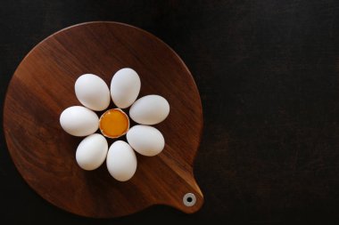 Çiğ yumurta sarısı koyu ahşap arka plan üzerinde bir çiçek içine katlanmış merkezi ile
