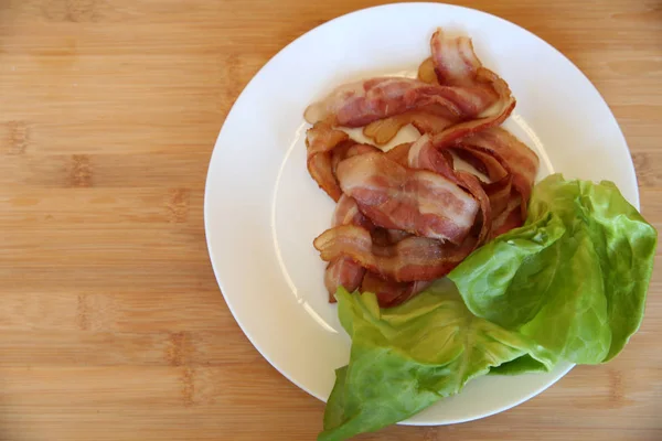 Tocino Frito Con Hojas Verdes Lechuga Plato Blanco Sobre Fondo — Foto de Stock