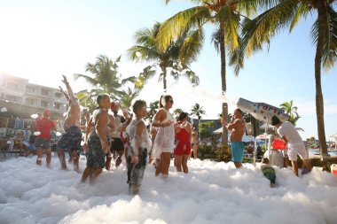 Holguin, Küba-11.25.2018 grup palmiye ağaçları altında sahilde bir köpük diskoda insan