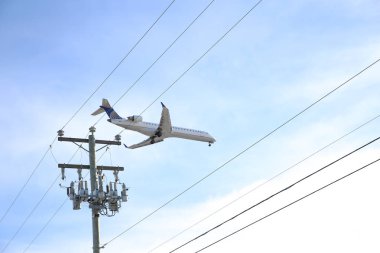 Uçak elektrik direği ve teller üzerinde mavi gökyüzünde