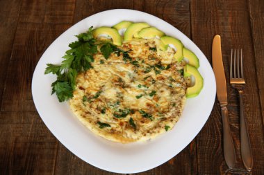 taze maydanoz ve beyaz plaka üzerinde avokado ile omlet