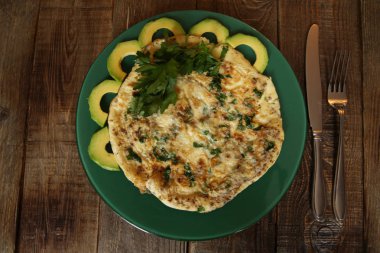 taze maydanoz ve avokado ahşap rustik arka plan üzerinde yeşil bir plaka ile omlet